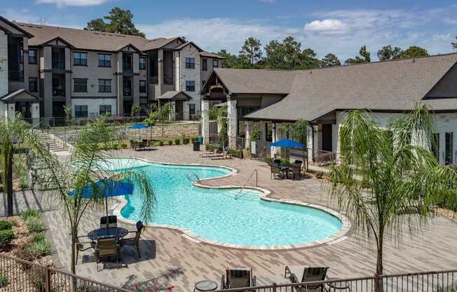 A large outdoor swimming pool surrounded by lounge chairs and trees.