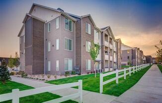 a row of town homes with a sidewalk and white fence  at Affinity 56 Apartments in West Jordan, Utah