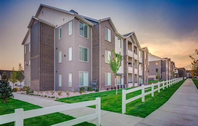 a row of town homes with a sidewalk and white fence  at Affinity 56 Apartments in West Jordan, Utah