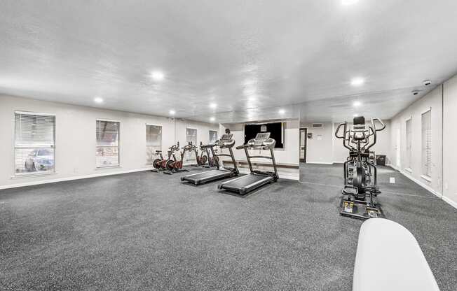 A spacious gym with a variety of equipment including treadmills, stationary bikes, and weight machines.