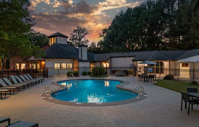 a swimming pool at dusk with a house in the background