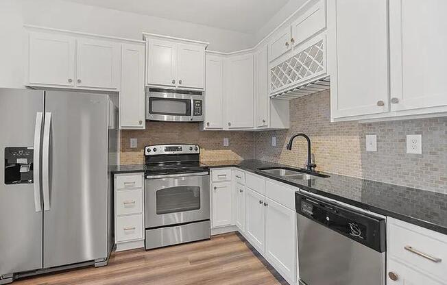 A kitchen with white cabinets and a black countertop.