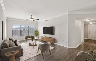 A living room with a grey couch, a wooden coffee table, and a flat screen TV mounted on the wall.