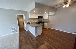 the view of a kitchen and living room from the entryway of an empty house