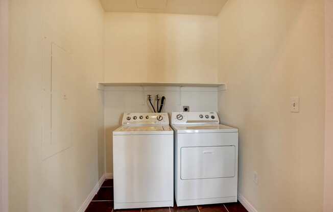 Two white front loading washing machines in a small laundry room.