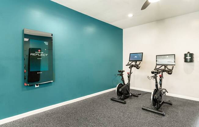 two exercise bikes and a water fountain in a room with a blue wall and a