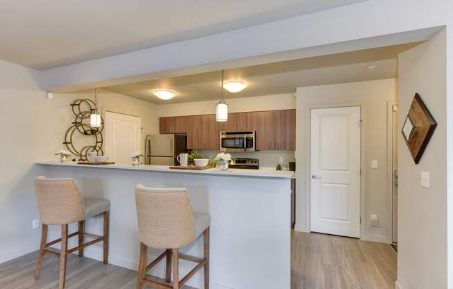 Model Kitchen with Counter,Stools, Hardwood Inspired Floor, Ceiling Lights, and Fridge/Freezer