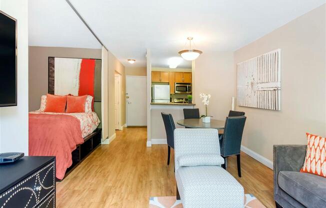 Model Floor Plan with Open Layout Hardwood Style Flooring a Couch an accent Chair and a DIning Table across from a Platform Bed