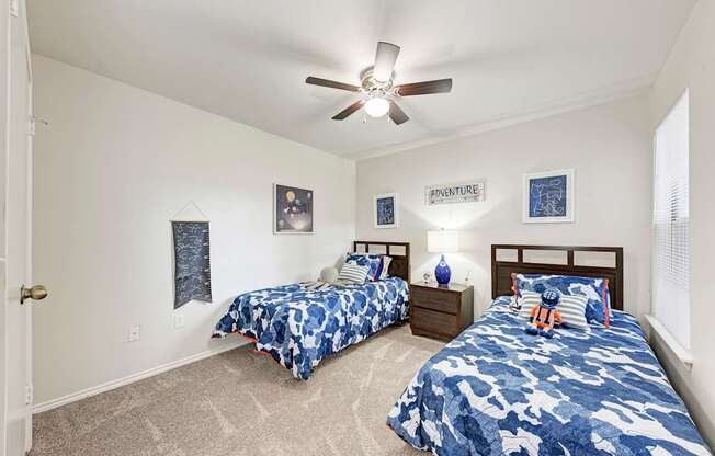 A bedroom with two beds and a ceiling fan.