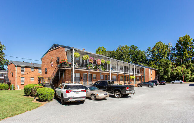 a large brick building with a balcony and a parking lot in front of it