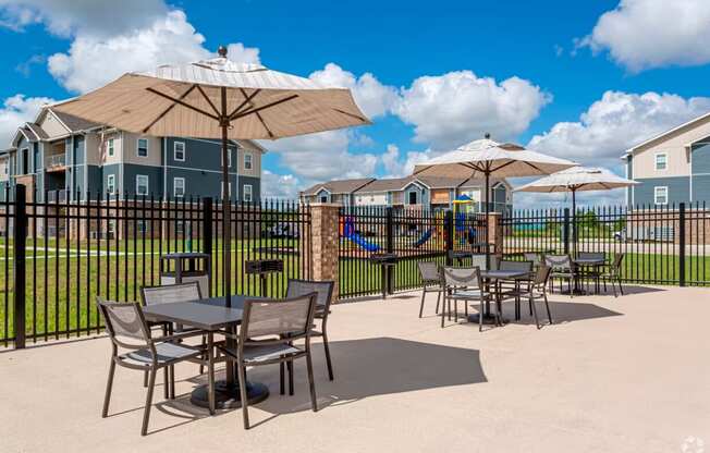 a patio with tables and umbrellas at the enclave at woodbridge apartments in sugar land