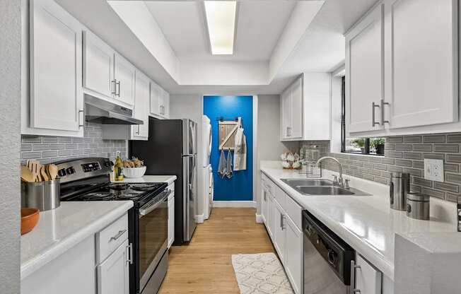 A modern kitchen with white cabinets and a black stove top oven.