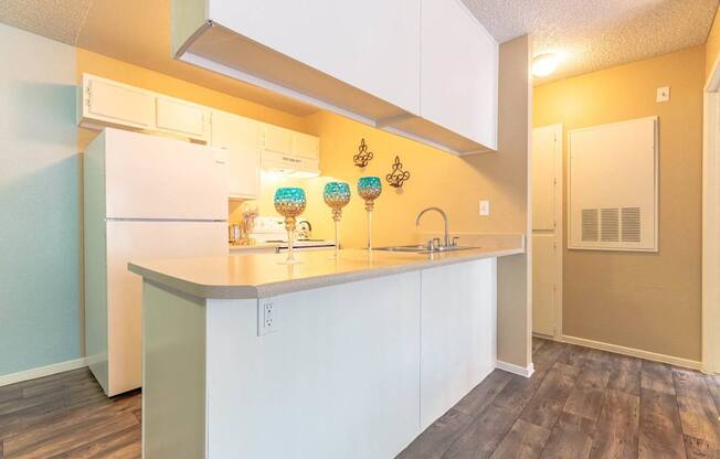 A kitchen with white cabinets and a white fridge.