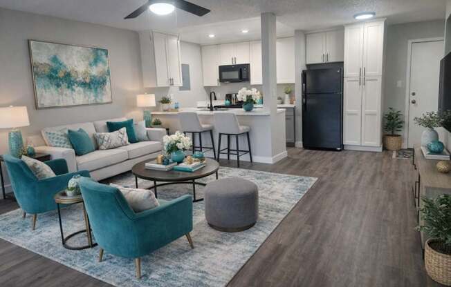 A modern living room with a white couch, a blue chair, and a painting on the wall.