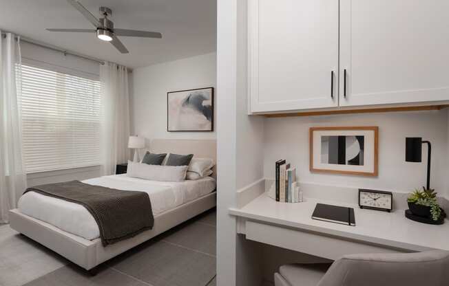 a bedroom with a white bed and a desk and a window