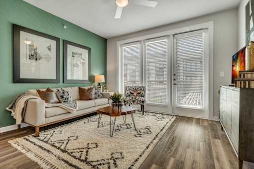 A living room with a couch, a coffee table, and a rug with a pattern on it.