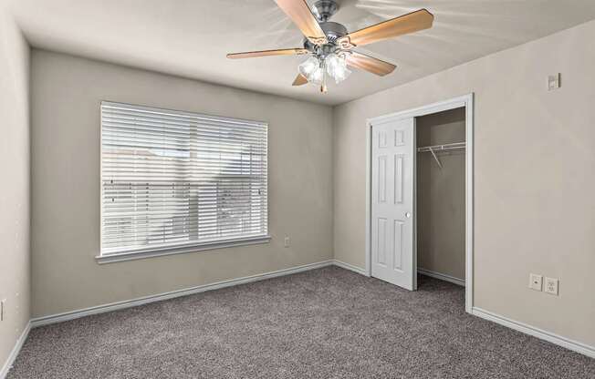A room with a ceiling fan and a window with blinds.