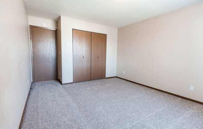 Grand Forks, ND Library Lane Apartments an empty bedroom with a closet and a carpeted floor