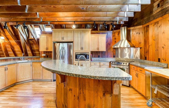 a kitchen with wooden cabinets and an island with granite countertops  at ReNew at Neill Lake, Minnesota, 55344