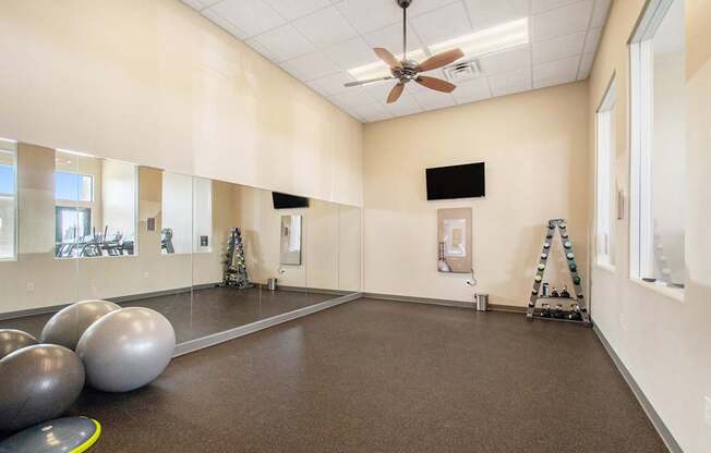 A room with a brown floor and a ceiling fan.