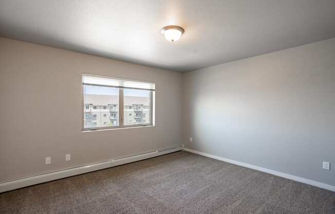 a bedroom with carpet and a window. Fargo, ND 29 West Apartments