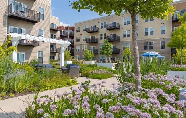 a garden with flowers in front of an apartment building