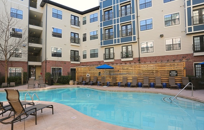 an outdoor pool with lounge chairs and a hot tub at the falls at rolland park apartments