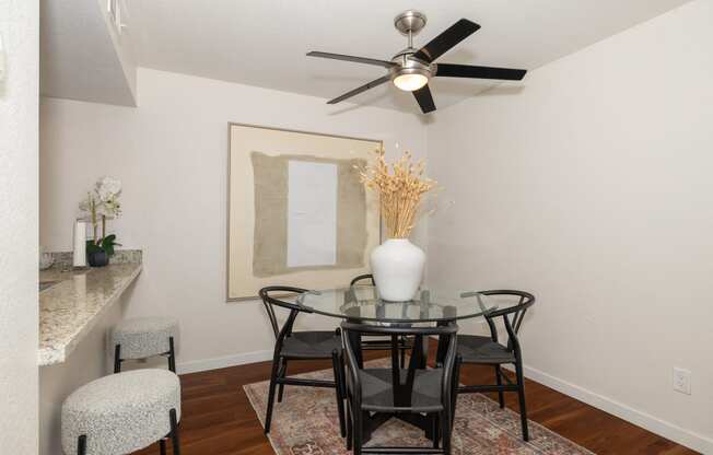 a dining room with a glass table and chairs and a ceiling fan at Rocklin Manor  Apartments, Rocklin  