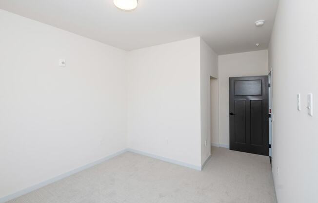 a living room with white walls and a black door at The Crossings at Windsong, Arizona