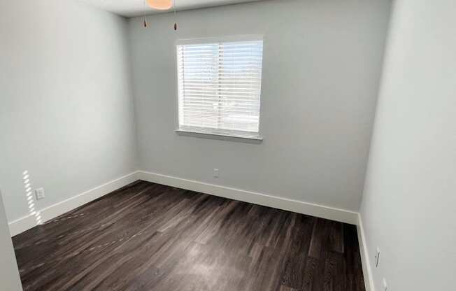 an empty room with wood flooring and a window