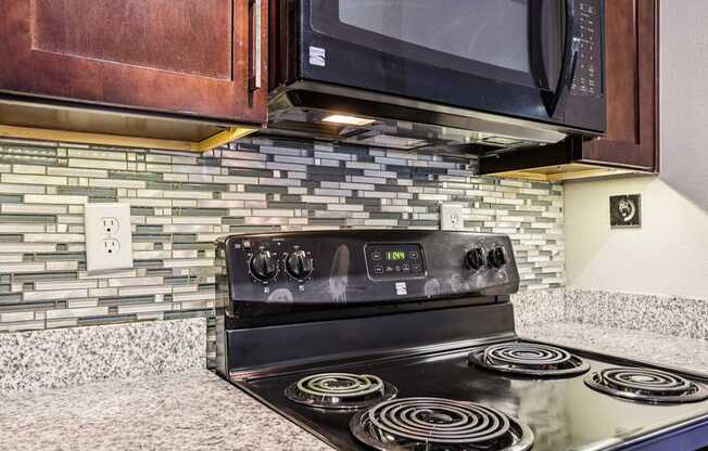 A black stove with four burners is in a kitchen with a tile backsplash.