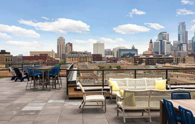 A rooftop patio with a table and chairs overlooking a city skyline.