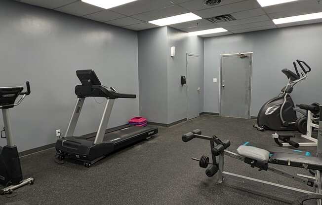 a gym with exercise equipment on the floor and a door