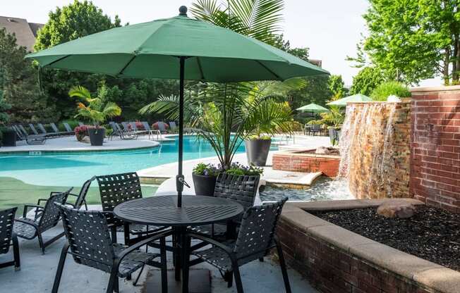 A patio with a table, chairs and an umbrella.
