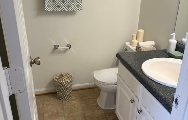 A bathroom with a toilet, sink, and trash can.