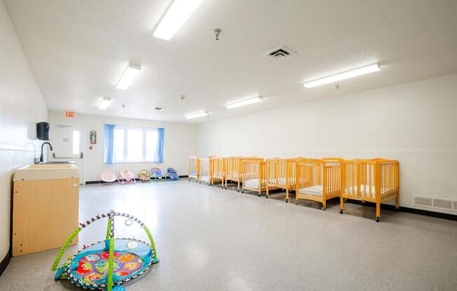 a multipurpose room with children cribs and a baby play area at Sutton Hill Apartments, IOWA