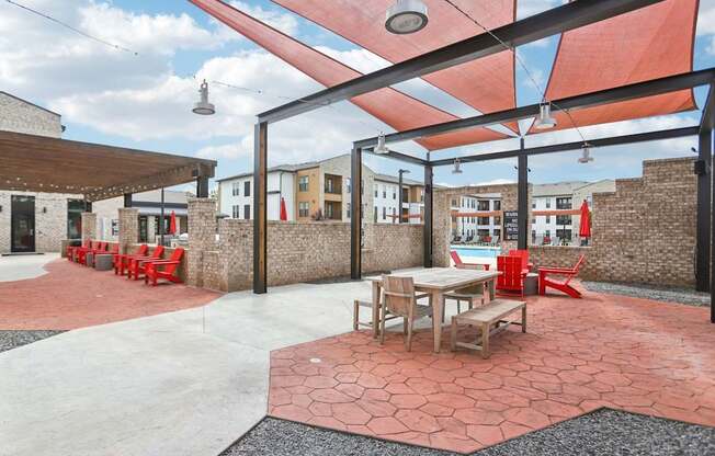 A patio with tables and chairs under a red awning.