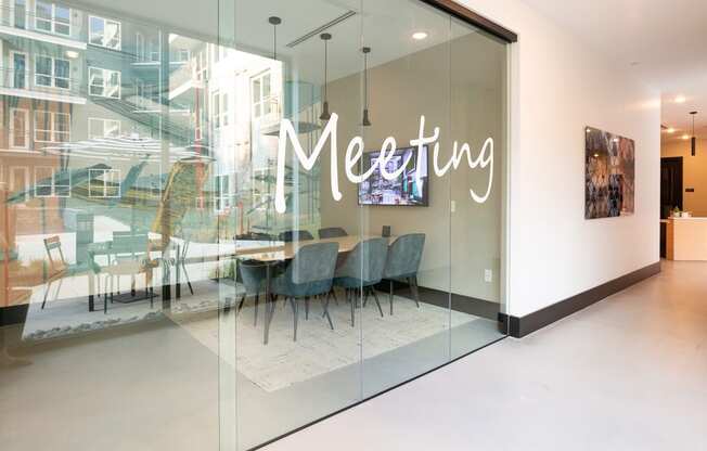 a meeting room with glass walls and a table and chairs