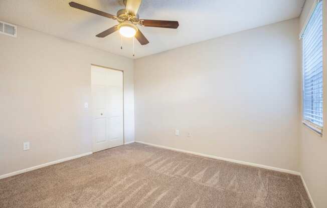A room with a ceiling fan and carpeted floor.