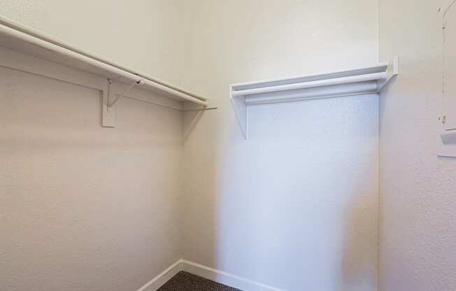 a walk in closet with a white wall and a sliding closet door