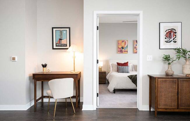 A room with a desk and a bed in the background.