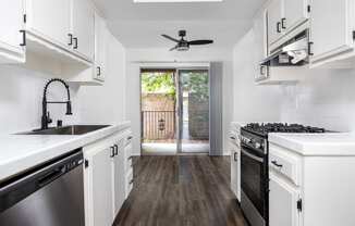 a kitchen with white cabinets and stainless steel appliances and a sliding glass door