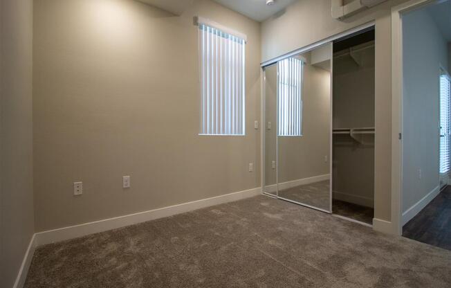 a bedroom with carpeted flooring and a large window at Loma Villas Apartments in San Bernardino, CA