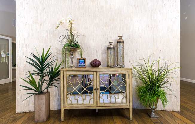 a wooden cabinet with glass doors with plants on top of it