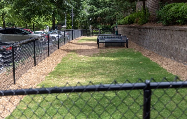 a park bench sitting in the grass next to a fence