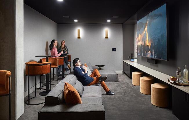 a man and two women sit on a couch in front of a flat screen tv in a