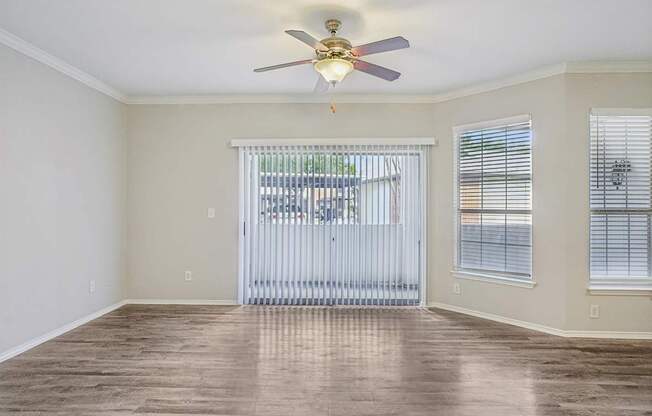 A room with a ceiling fan and sliding glass doors.