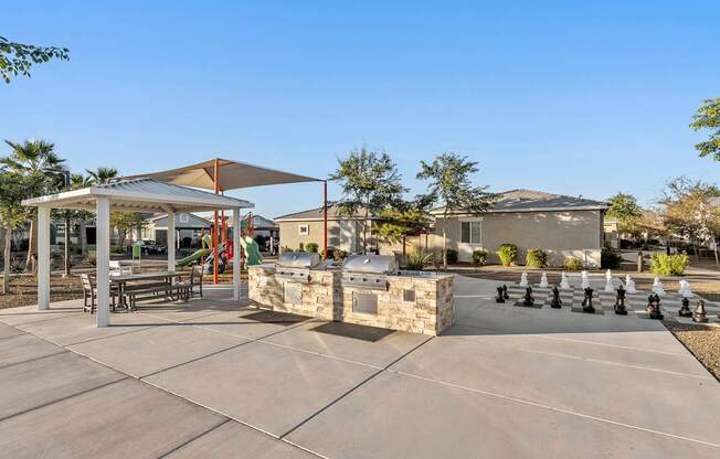 A playground with a chess board in the middle of the pavement.