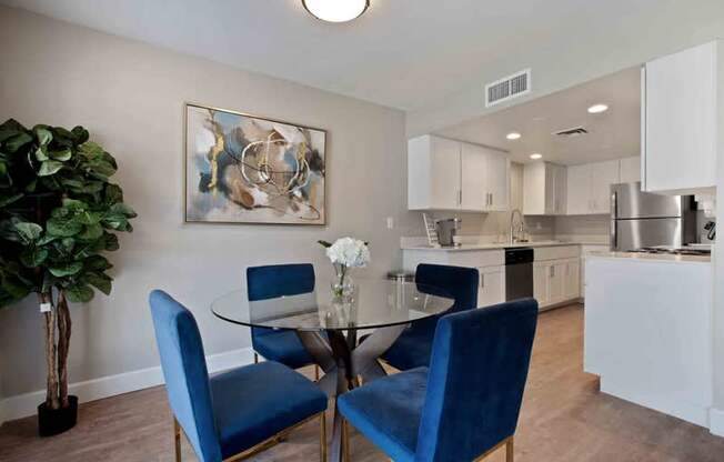 A dining room with a glass table and blue chairs.