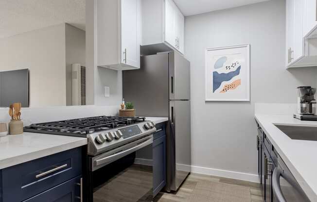 an open kitchen with stainless steel appliances and white counters and a refrigerator